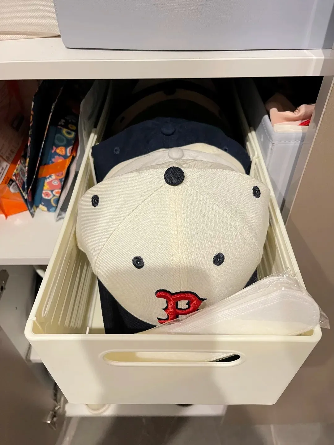 Baseball caps neatly organized in a closet storage bin.